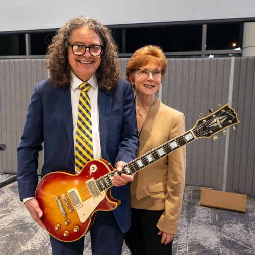 Jeff Myers with his wife, Eileen McMyler, and the Les Paul guitar he received as a parting gift from the department.